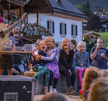 Kinder vor Freilichtbühne blicken Richtung Musiker